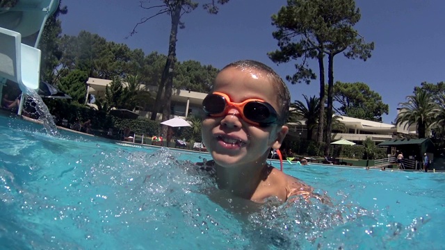 男孩在游泳池滑梯上滑-在游泳池里跳和跳水视频下载