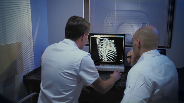 在控制室，医生和放射科医生一边看程序一边讨论诊断。MRI或CT扫描程序。视频素材