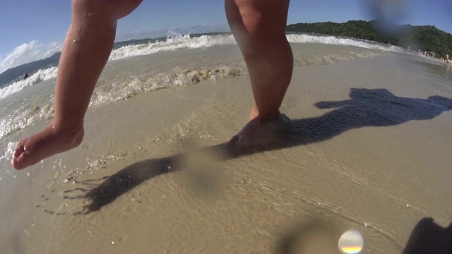 在海滩/海边散步的婴儿/蹒跚学步的小孩。脚近距离。高清视频下载
