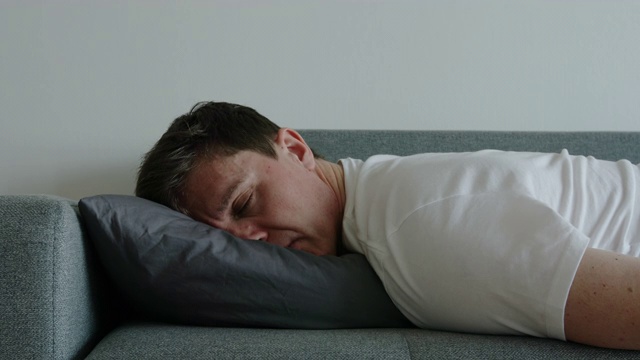 抑郁:一个年轻人在枕头上翻个身睡觉的肖像视频素材