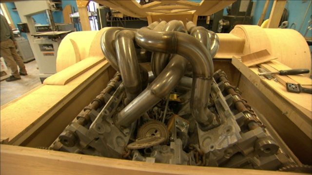 一辆支离破碎的汽车的木框架里装着一个大引擎。视频下载