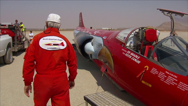 Ed Shadle穿着飞行服走在“北美鹰”旁边，与支持他的机组人员交谈。视频下载
