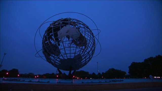 夜晚，一座巨大的地球雕塑耸立在城市公园的上空。视频素材