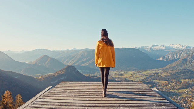 MS年轻女子走到平台的边缘，俯瞰阳光明媚，风景优美的山景，失败者山，奥地利视频素材