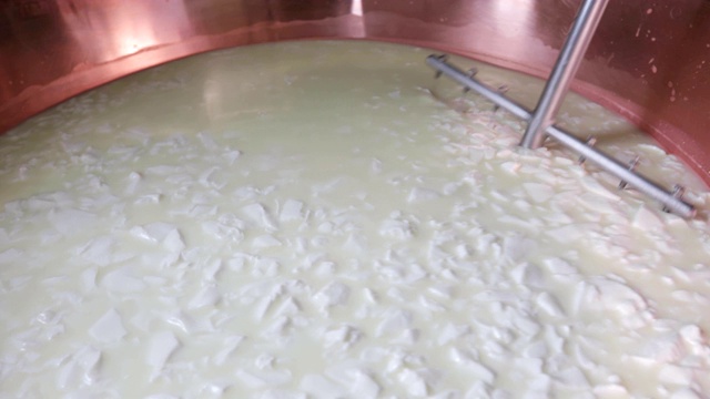 农民在加热羊奶生产奶酪时搅拌羊奶的特写镜头视频下载