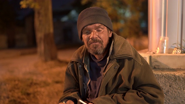 无家可归的病人晚上在街上抽烟。视频素材