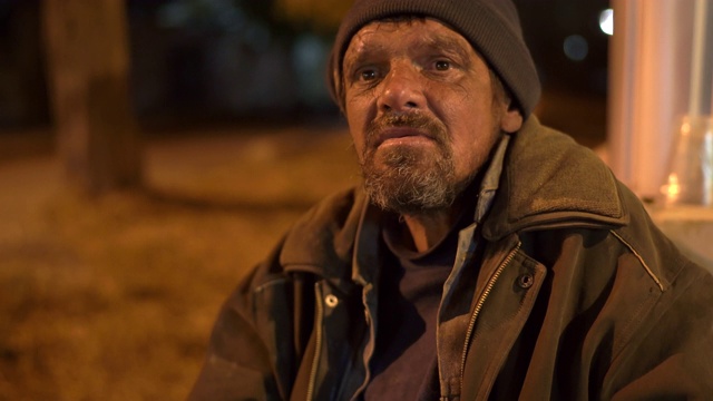 一个路人晚上在人行道上和一个无家可归的人聊天。视频素材