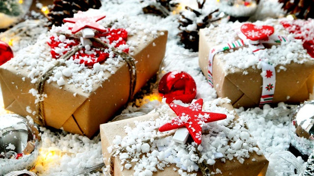 圣诞节和新年的背景与礼物，丝带，球和不同的装饰上的雪。礼物用牛皮纸包装，上面有红星图案。视频素材