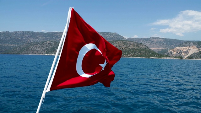 在晴朗的日子里，土耳其国旗在地中海的风中飘扬。视频下载