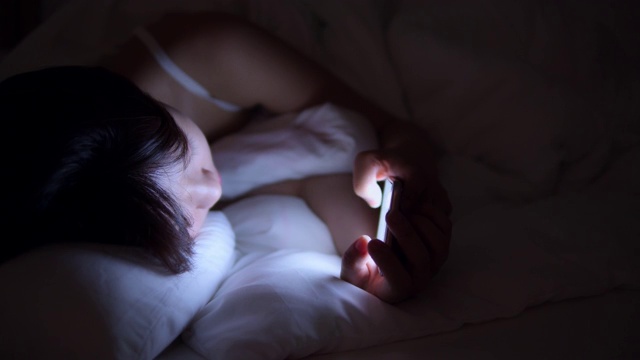 女人晚上在床上使用手机视频下载