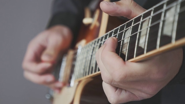男性的手在弹奏电吉他近距离。手指在吉他指板上拿着拨片弹奏和弦和独奏。乐器的概念视频素材