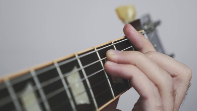 手指在吉他弦上弹奏独奏和和弦。近视图的吉他指板和使手指。音乐的概念视频素材