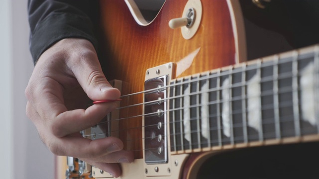男人用手挑弹奏电吉他挑和拨弦。男性的手和吉他弦与拾音器演奏摇滚歌曲。音乐的概念视频素材