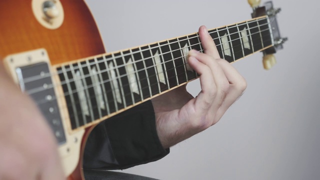 用手弹奏电吉他或原声吉他。用吉他弹奏摇滚和蓝调和弦。手，手指放在吉他指板上视频素材