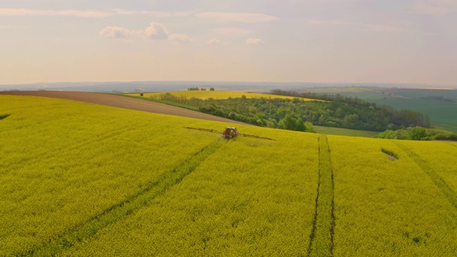 空中喷洒农药的农民在油菜田周围的风力涡轮机视频素材