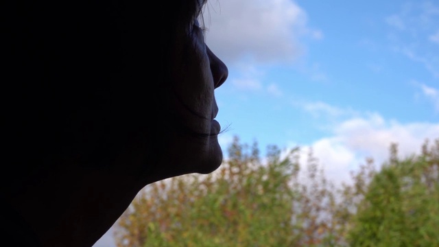 妇女一边祈祷一边望着窗外的天空。视频素材