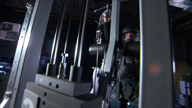 一个穿着机械盔甲的人在通用机器上举起重物。视频下载