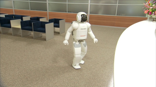 一个ASIMO机器人在接待处附近的大厅里走动并转弯。视频下载