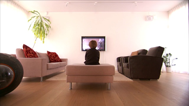 一个男孩坐在沙发上看电视。视频素材
