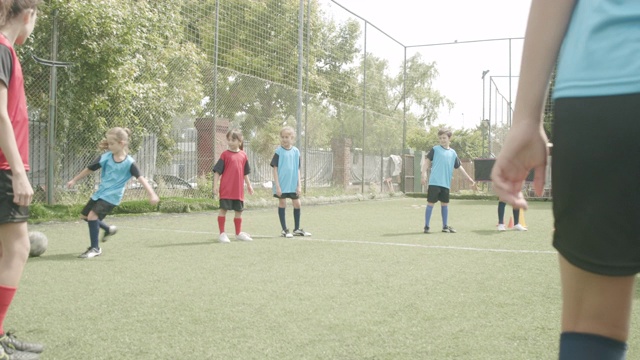 一群孩子和他们的教练一起踢足球视频素材