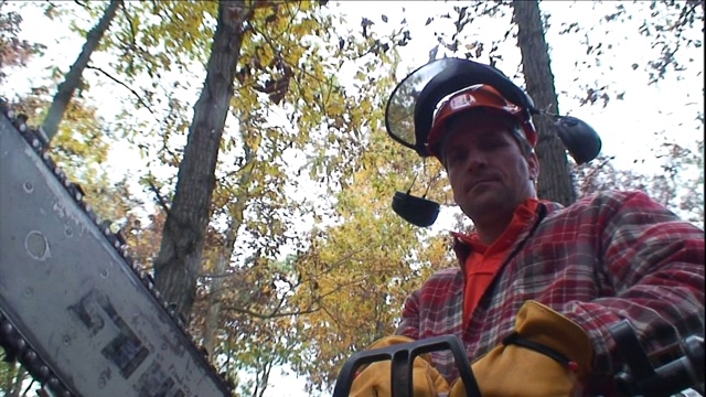 一个伐木工在森林里拿着一个链锯。视频下载