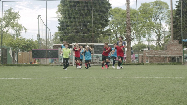 一群孩子一起庆祝在足球场上赢得比赛视频素材