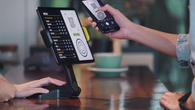 近距离的顾客在咖啡厅柜台柜台用平板电脑使用手机支付。小型企业开始。客户服务理念视频下载