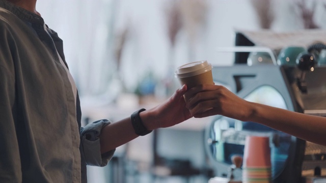 亚洲女咖啡师小企业主在咖啡店的柜台酒吧提供咖啡杯。开创年轻人的事业。慢动作视频下载