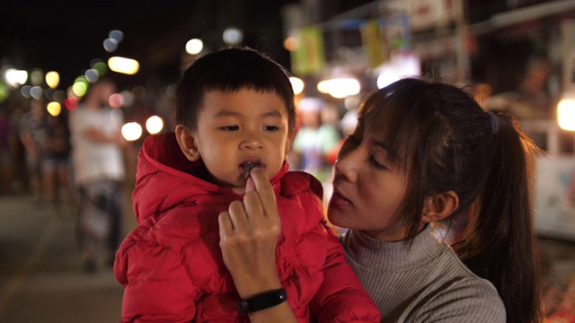 小男孩和他妈妈在夜市吃街边小吃，4K视频素材