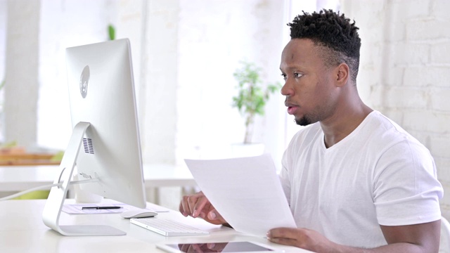 漫不经心的非洲人在办公室用电脑做文书工作视频素材