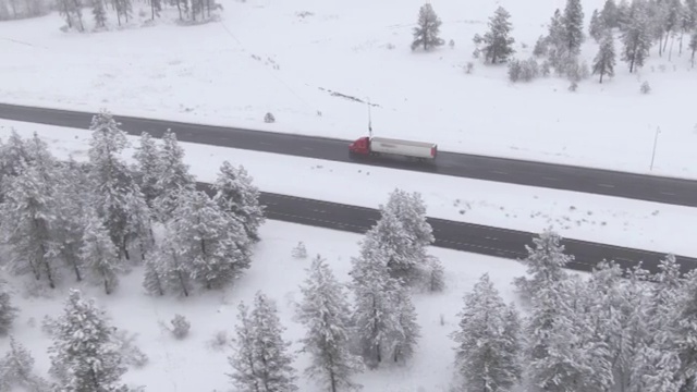 无人机:大型商用卡车在危险的结冰公路上拖着一个沉重的集装箱。视频素材