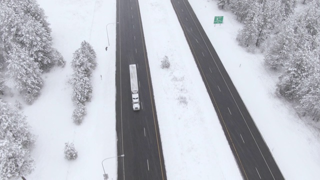 空中摄影:在暴风雪中，一辆卡车在滑溜的高速公路上飞驰。视频素材