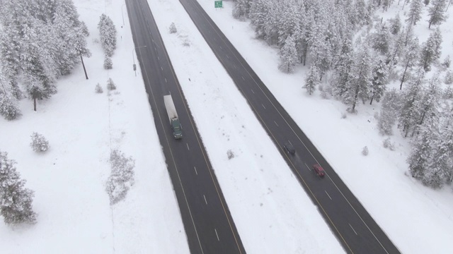 无人机:在暴风雪期间，在滑滑的公路上驾驶的18轮大卡车上方飞行视频素材