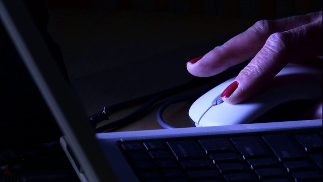 一位涂了指甲油的女士正在使用电脑鼠标和笔记本电脑。视频素材