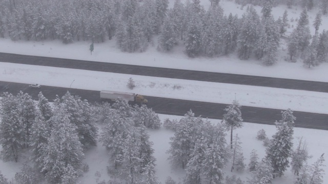 无人机:大18轮卡车在暴风雪中沿着光滑的公路飞驰视频素材