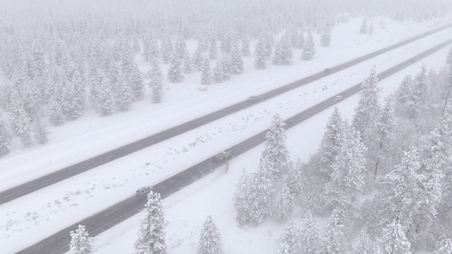 无人机:在冬季常绿森林上空，扫雪机正在清理结冰的公路视频素材