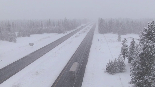无人机:货车和汽车在暴风雪中穿行，沿着潮湿的公路行驶。视频素材