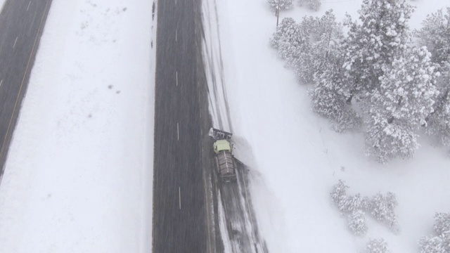 航拍图:在暴风雪中，铲雪车在高速公路上清理并撒盐。视频素材