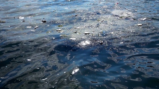 漂浮在水面上的垃圾。海面上漂浮的污物和塑料垃圾造成的水污染视频素材