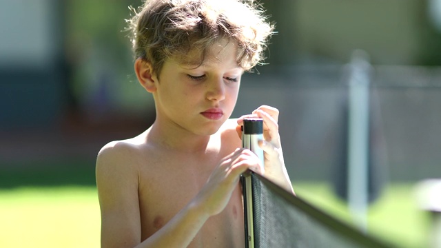 孩子的肖像旁边的游泳池围栏无聊的情绪视频素材