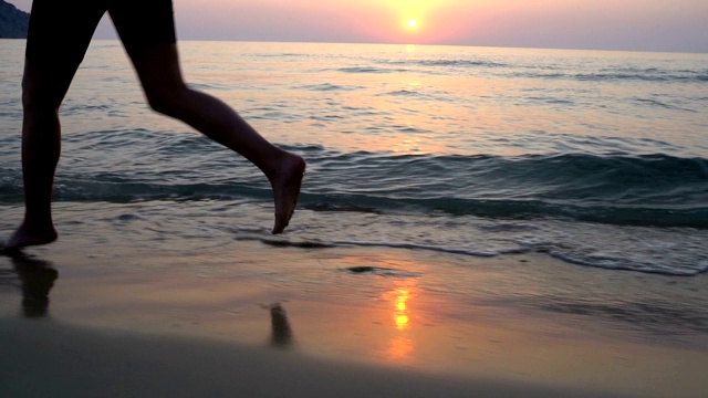 日出时，年轻女子在海滩上冲过海浪视频素材