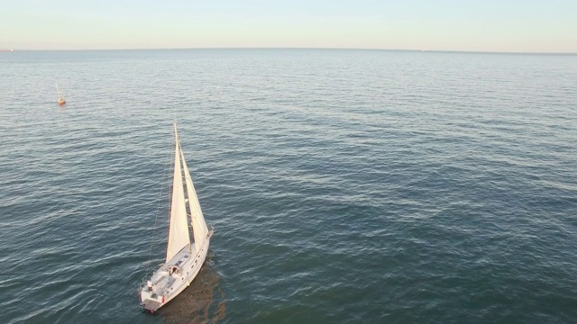 近海岸线航行的帆船鸟瞰图。蓝色的大海和阳光的反射。无人机视图-鸟瞰角度。视频素材