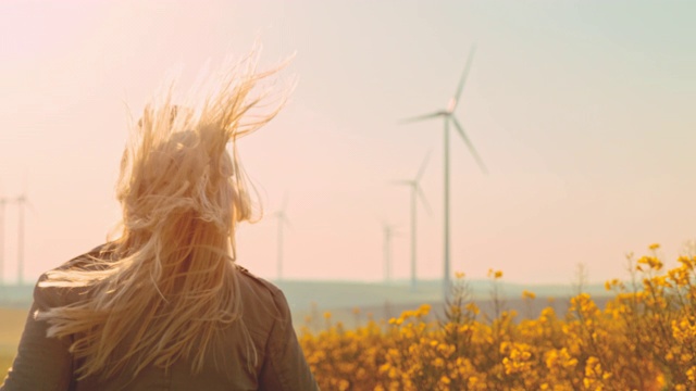 超级慢的MO -时间扭曲效应女人与金发运行在风力涡轮机视频下载