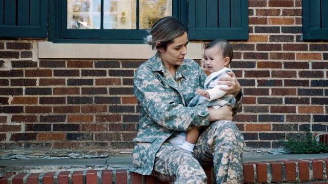 女士兵安慰她哭泣的女婴视频素材