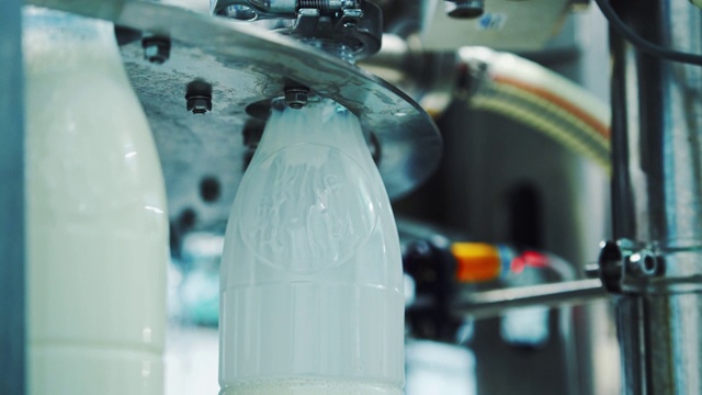 在一家现代食品厂，牛奶正被倒入塑料瓶中。视频下载