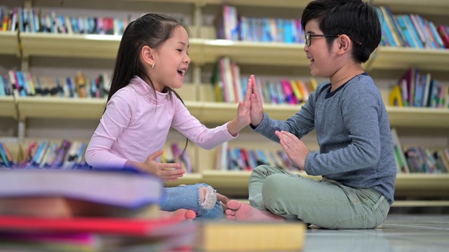亚洲小女孩和男孩在学校图书馆一起玩视频素材