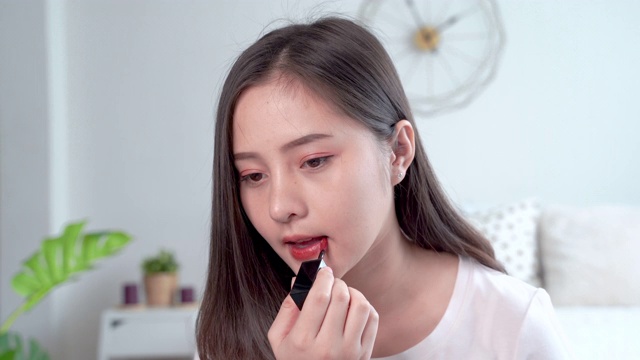 美丽的亚洲女性用刷子在嘴唇上涂口红来化妆。视频素材