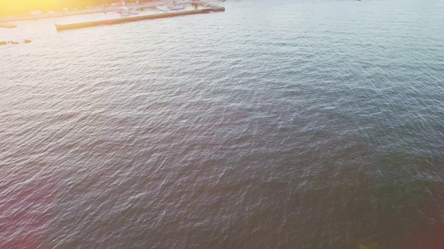 阳光明媚的傍晚，游艇从绿色海岸远航的鸟瞰图视频素材