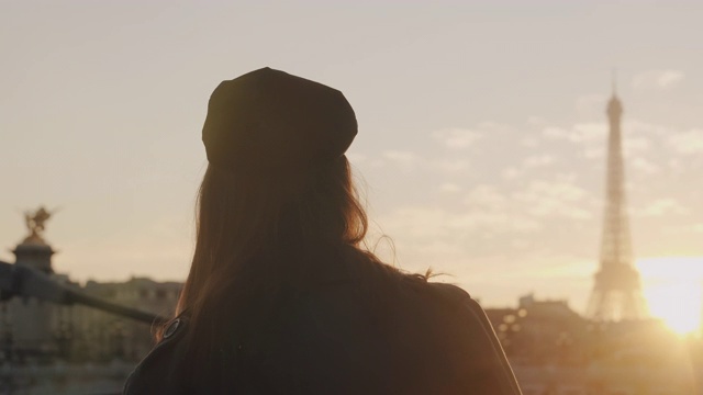 电影的后景，女游客看日落在著名的埃菲尔铁塔在巴黎，寻找灵感的慢动作视频素材
