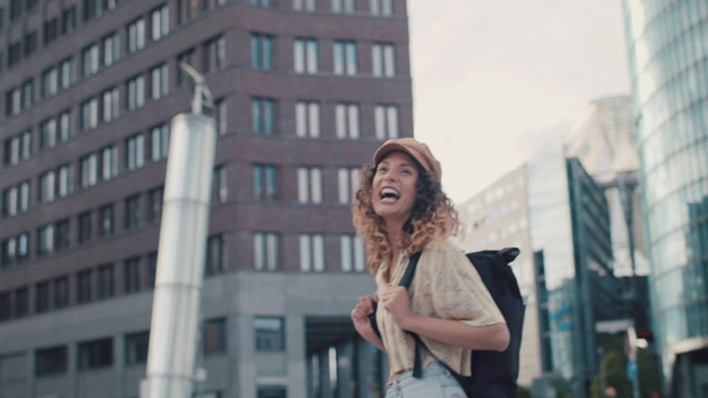 一名背着背包戴着帽子的年轻女子在柏林市中心大笑视频素材